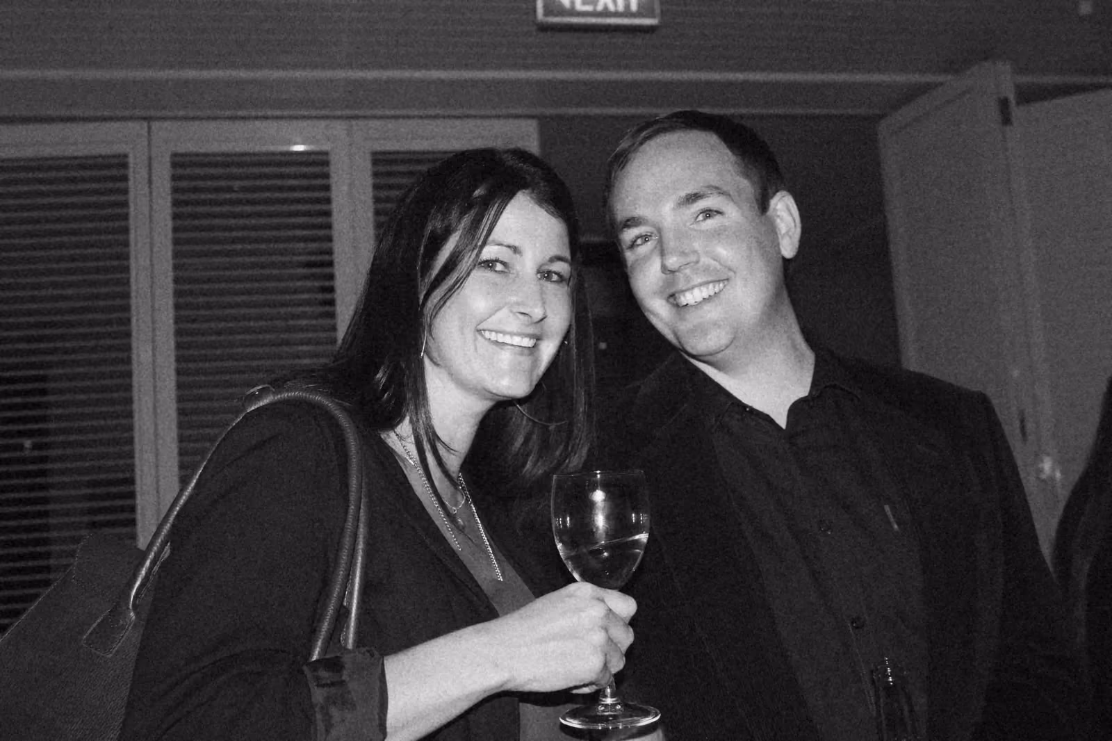 Ben and a guest smiling at an evening industry event, a glass of wine in her hand