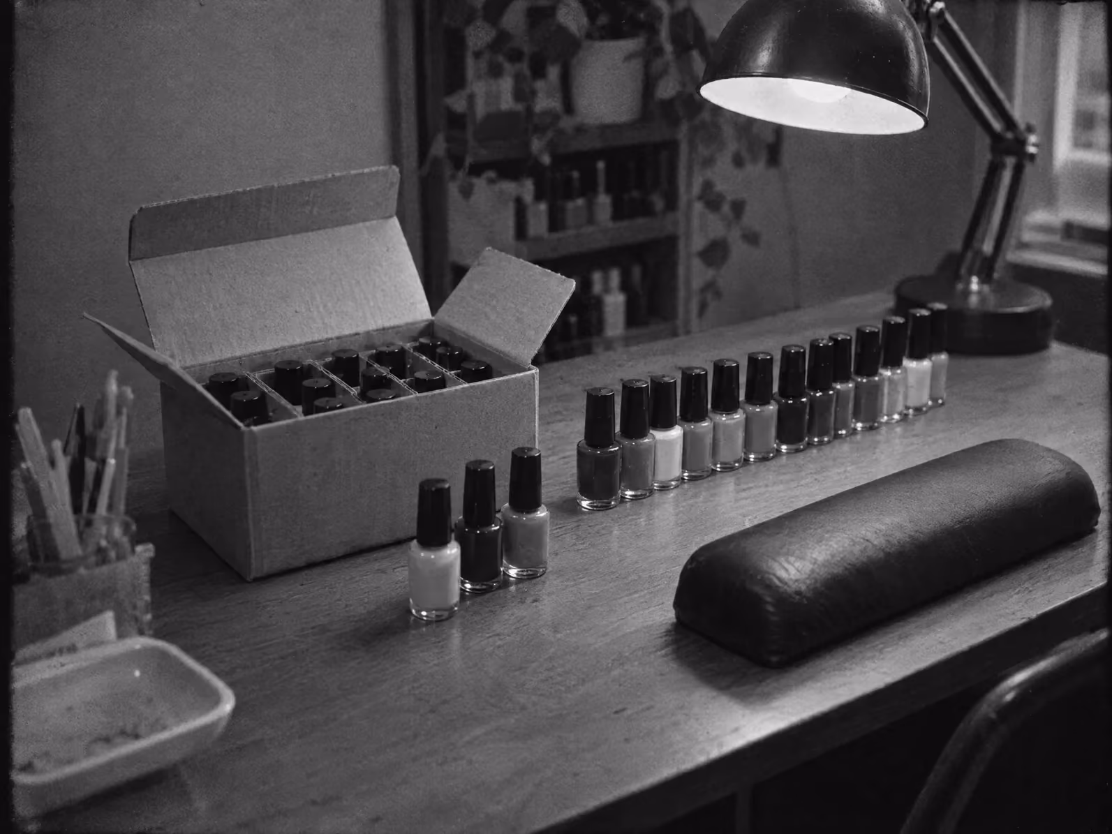 A carton of nail polish being unpacked on a nail desk, a row of bottles beside it