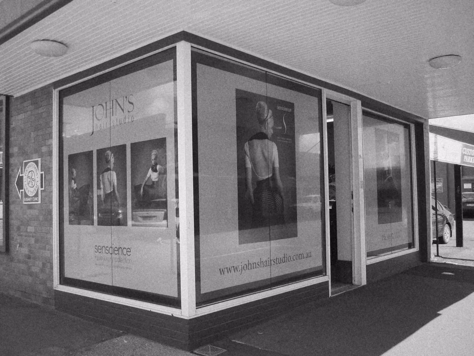 The finished Senscience window posters on the corner shopfront of John’s Hair Studio