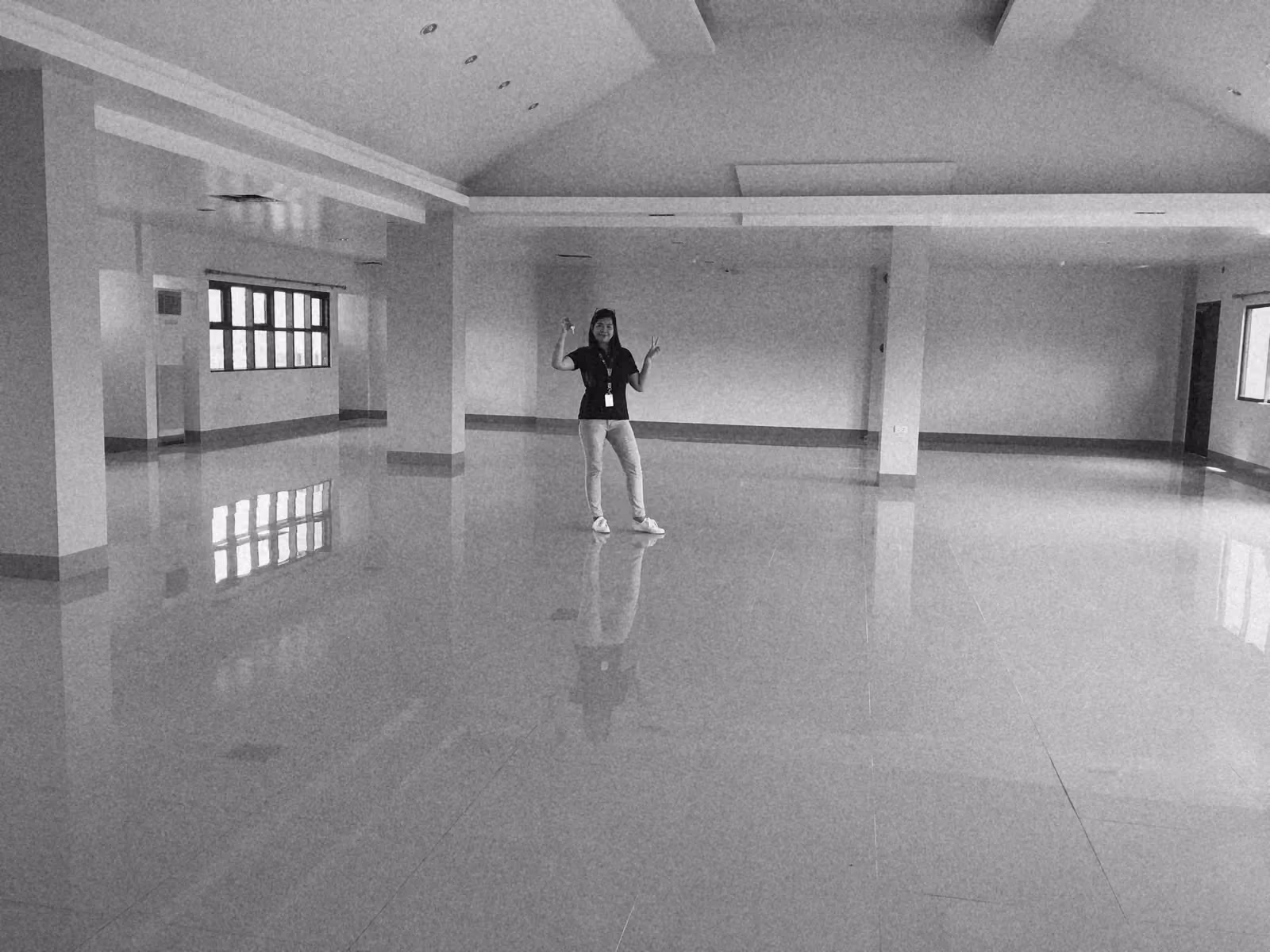A long, bare office floor with white tiles and a vaulted ceiling