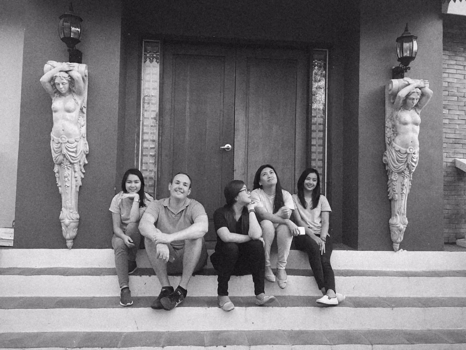 Ben sitting with four team members on stone steps in front of carved timber doors