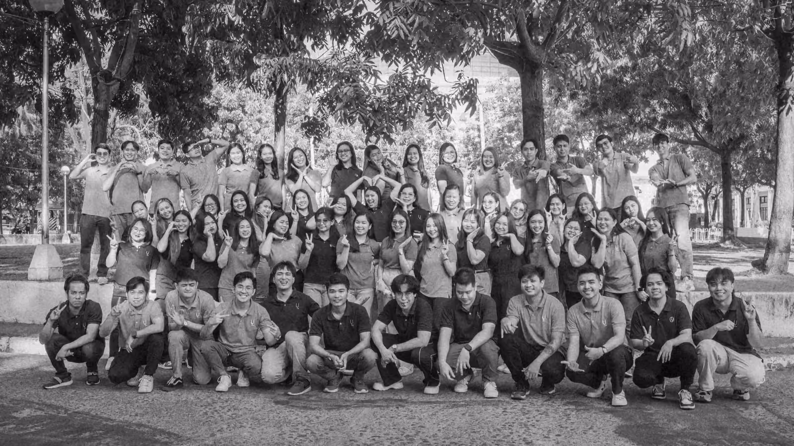 The whole team gathered outdoors under the trees, smiling at the camera