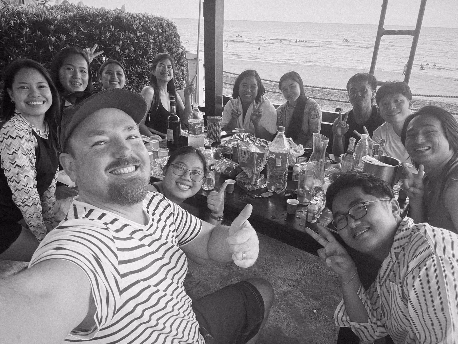 Ben taking a selfie with team members at a table by the beach