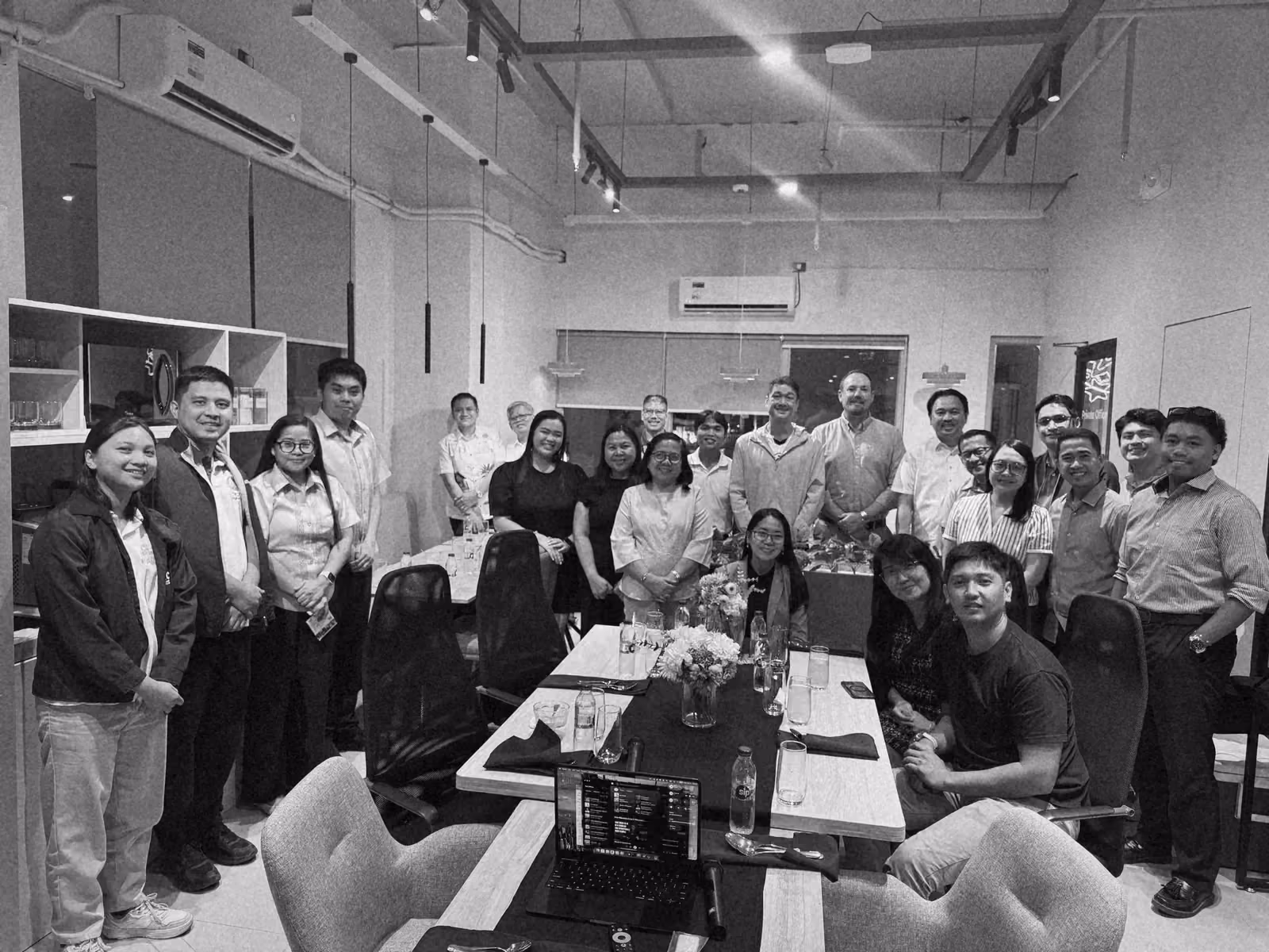 Ben with team members and guests around a set dinner table in a modern office